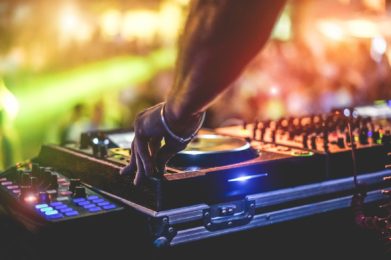 Dj mixing outdoor at beach party festival with crowd of people in background