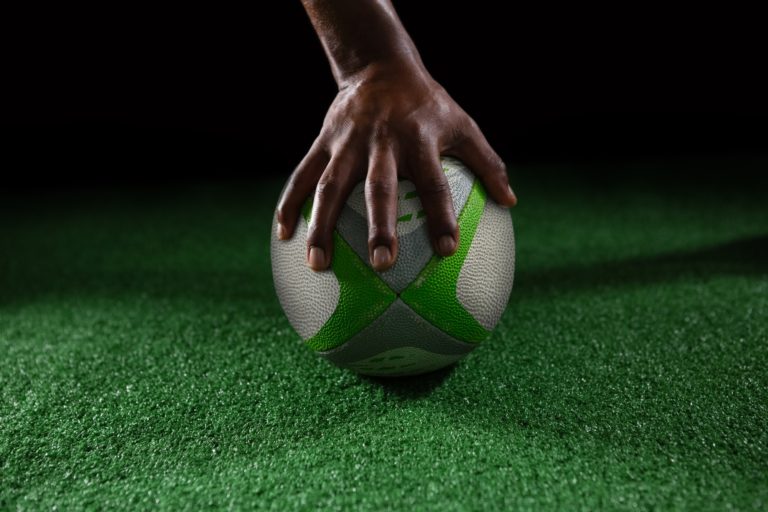 Cropped hand of person on rugby ball