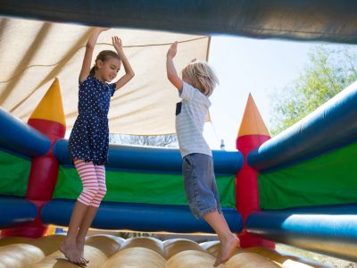 Happy siblings jumping on bouncy castle